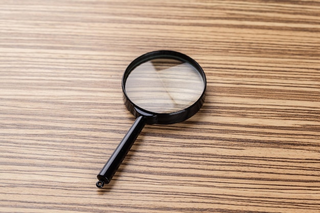 Free photo magnifying glass on the wooden background