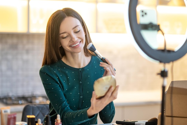 Free photo make up. woman holding face brush and doing make up