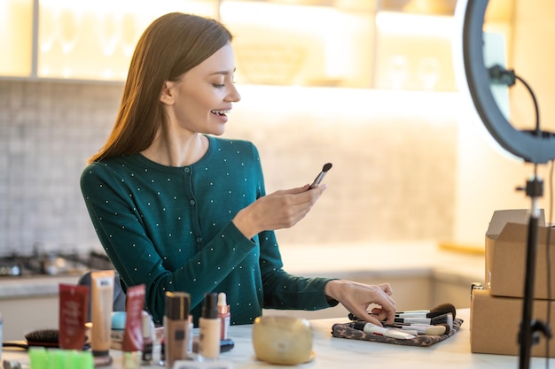 Free Photo make up. woman holding face brush and doing make up