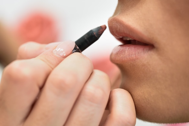 Makeup artist making up lips of an African young woman