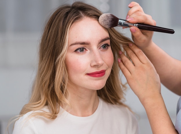 Makeup artist powdering forehead of woman 