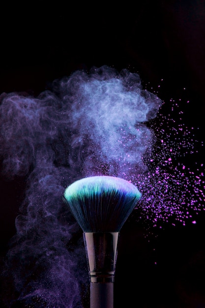 Free photo makeup brush with blue powder splash