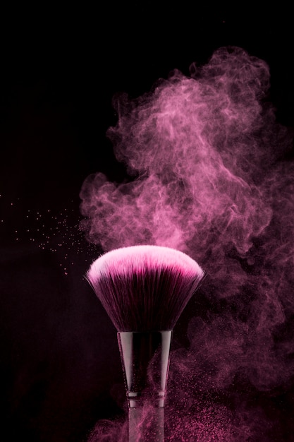 Makeup brush with flickering pink powder splash