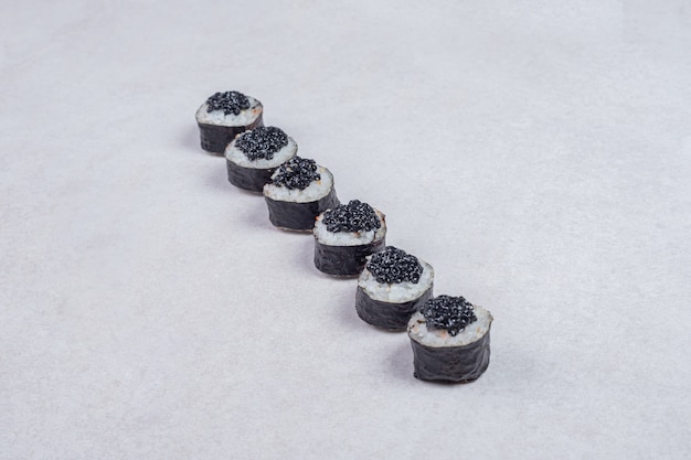 Maki rolls decorated with black caviar on white background.