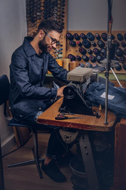 Free photo making clothes. tailor sitting at table and working on a sewing machine at the sewing workshop.