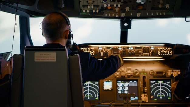 Free Photo male airline captain fixing altitude and longitude buttons, using dashboard navigation command and control panel. flying airplane with aircrew and radar compass, power engine and windscreen.