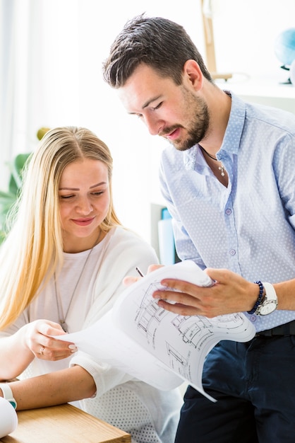 Free Photo male architect showing blueprint to his female colleague