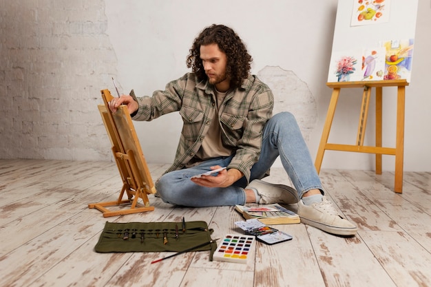 Male artist painting at studio with watercolors