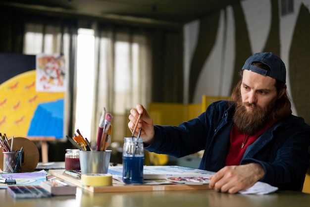 Free photo male artist painting with watercolor in the studio