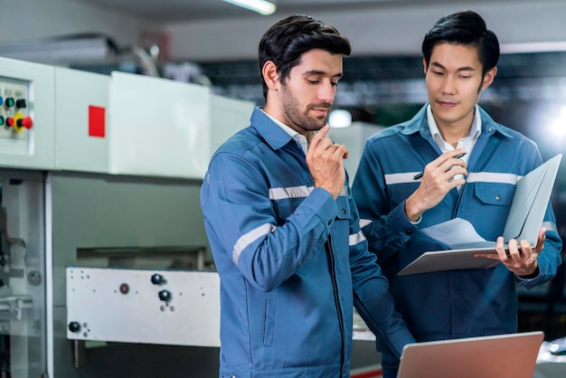 Free photo male asian caucasian engineer professional having a discussion standing consult at machine in the factory two expert coworker brainstorm explaining and solves the process of the cnc operate machine