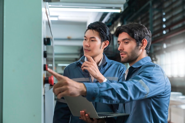 Free photo male asian caucasian engineer professional having a discussion standing consult at machine in the factory two expert coworker brainstorm explaining and solves the process of the cnc operate machine