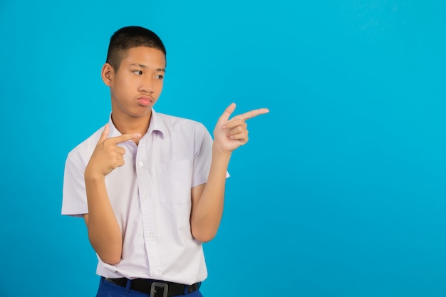 A male Asian male student with a hand raised his gesture pointing against the blue .