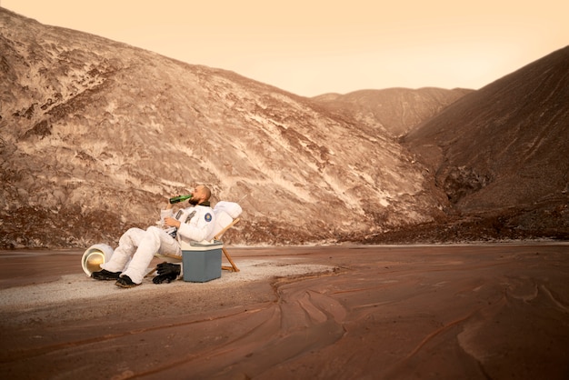 Free photo male astronaut drinking a beer during a space mission on an unknown planet