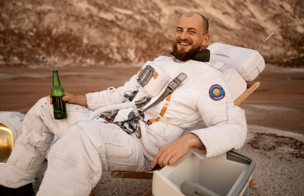 Free photo male astronaut drinking a beer during a space mission on an unknown planet