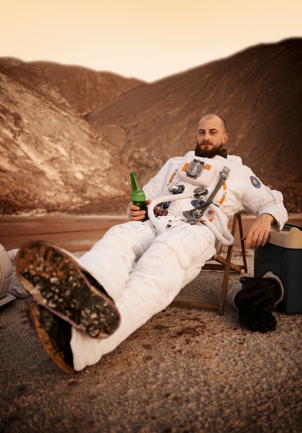 Free photo male astronaut drinking a beer during a space mission on an unknown planet