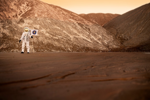 Free photo male astronaut holding a flag stuck in soil on an unknown planet