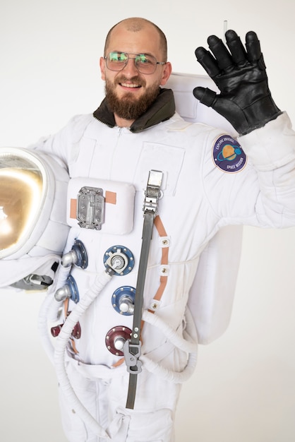 Free photo male astronaut waving and holding his helmet