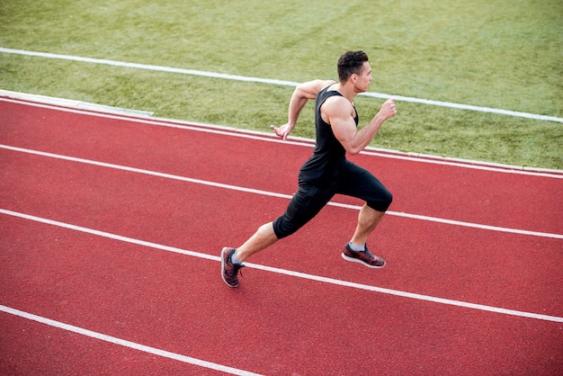 Male athlete arrives at finish line on racetrack during training session