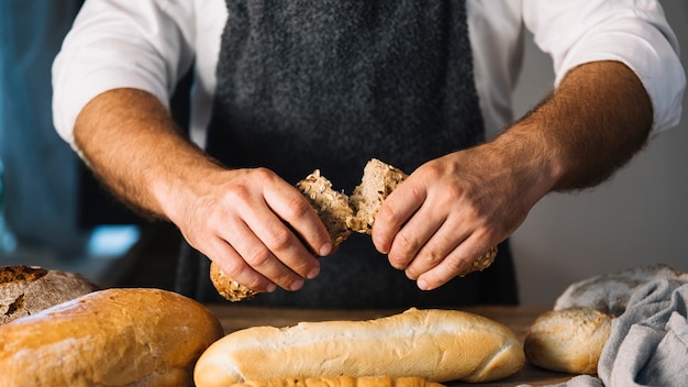 Free photo male baker holding freshly baked bread in the bakery