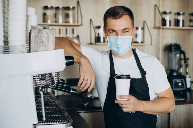 Free photo male barista holding coffee in cardboard cup