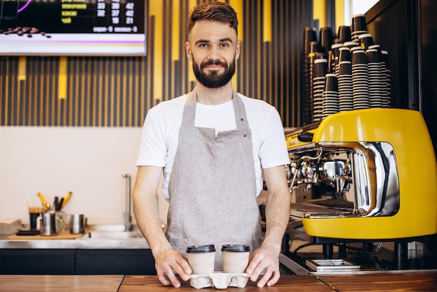 Free photo male barista serving coffee in cardboard cups