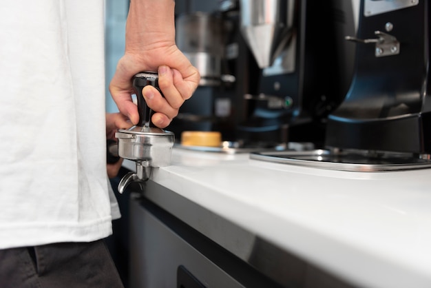 Male barista with tattoos at work using the coffee machine