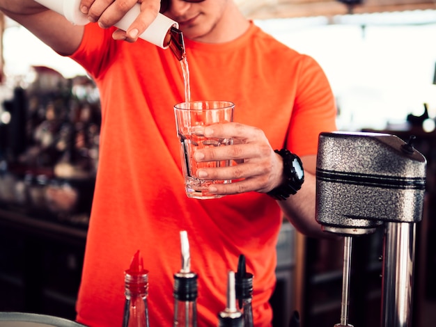 Free Photo male bartender filling glass with clear drink 