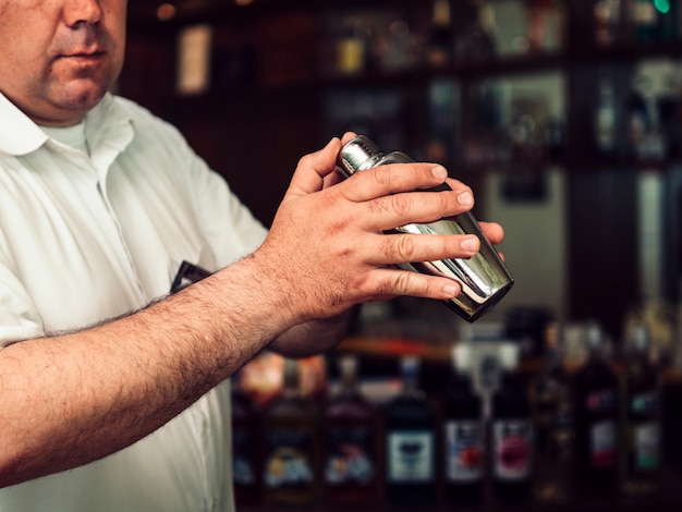 Free photo male bartender preparing drink in shaker