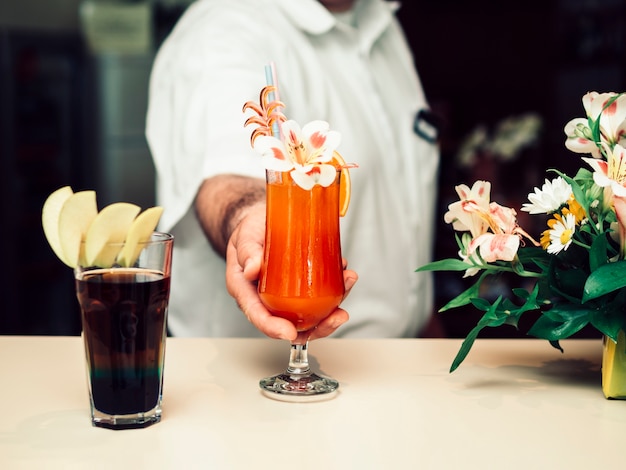 Male bartender serving colourful decorated drink