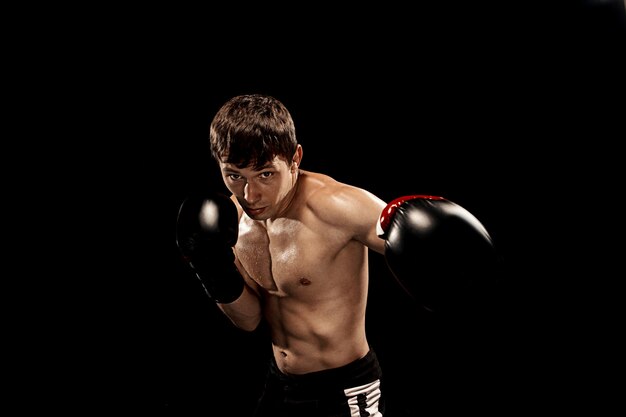 Male boxer boxing in punching bag with dramatic edgy lighting on black