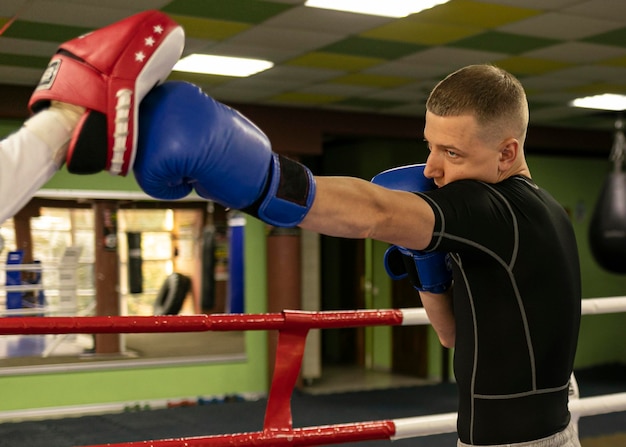 Male boxer with gloves exercising with trainer