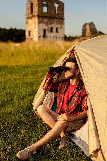 Free photo male in camping tent looking through binocular