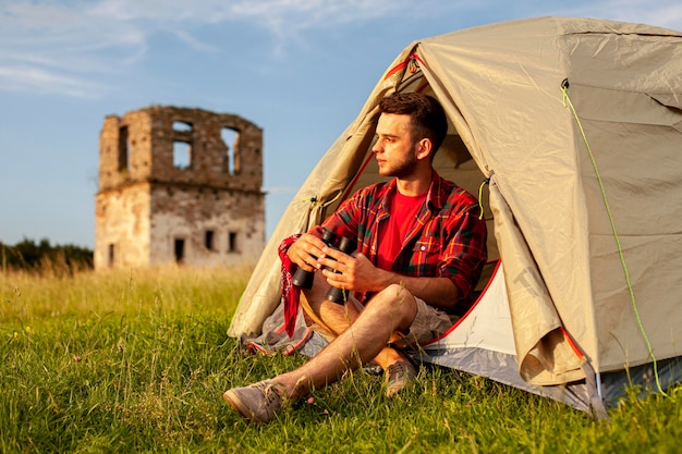 Male in camping tent with binocular