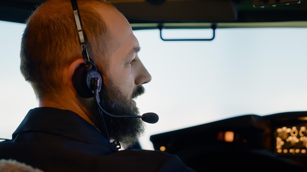 Free photo male captain pilot flying airplane with dashboard command, using aerial navigation to takeoff. control panel buttons with radar compass and windscreen, international flight service. close up.