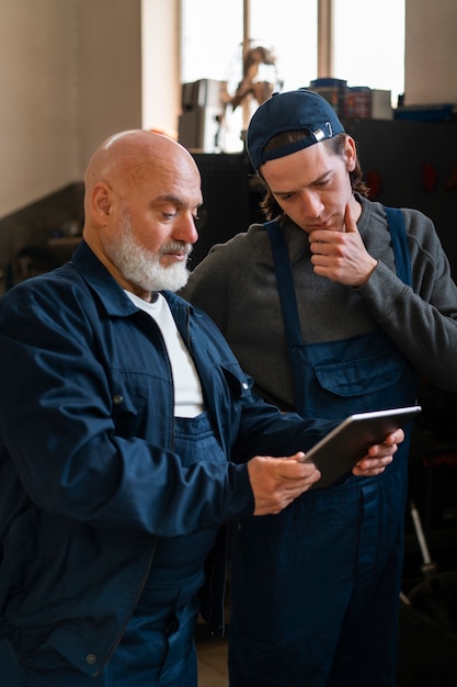 Free photo male car mechanic using tablet device in the car repair shop