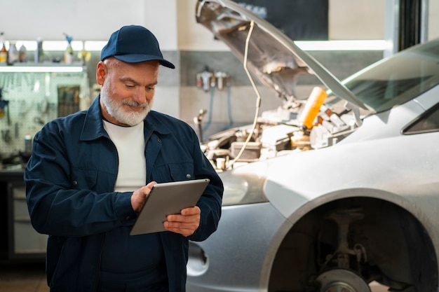 Male car mechanic using tablet device in the car repair shop