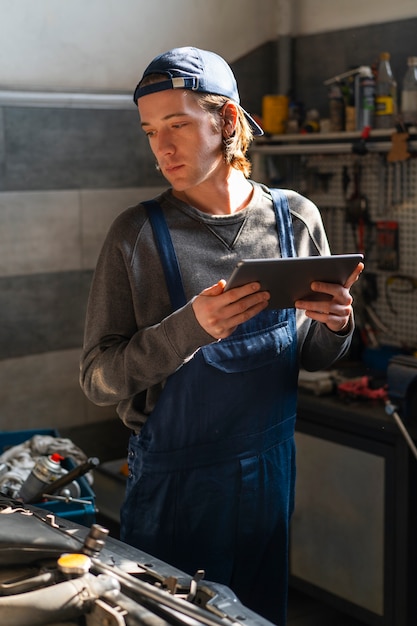 Male car mechanic using tablet device in the car repair shop