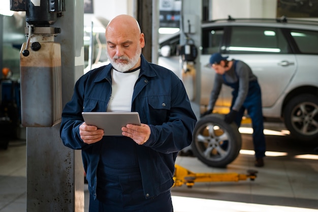 Free Photo male car mechanic using tablet device in the car repair shop