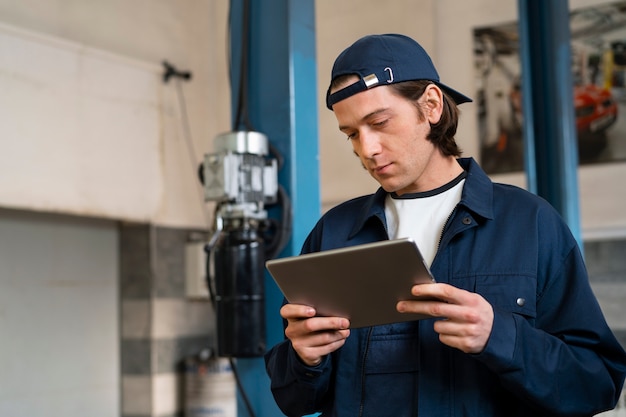 Free photo male car mechanic using tablet device in the car repair shop