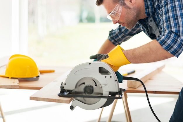 Free photo male carpenter sawing wooden boards