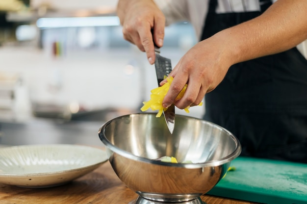 Male chef adding chopped bell pepper in bowl