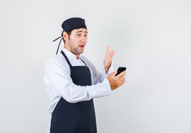 Male chef getting angry on videocall in uniform, apron , front view.