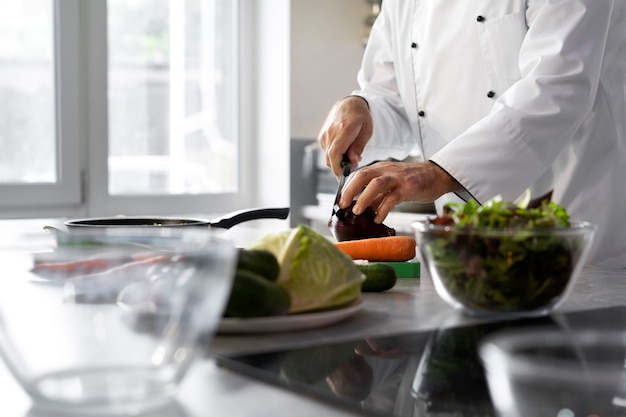 Free photo male chef in the kitchen chopping vegetables for dish