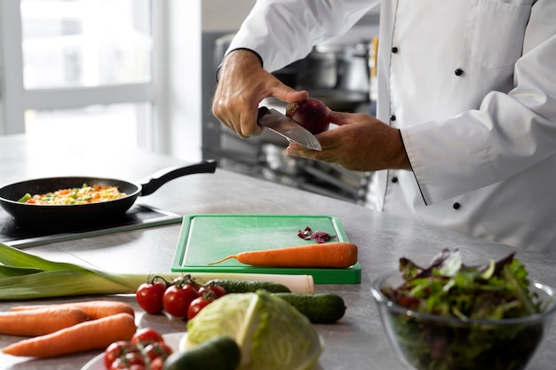 Free Photo male chef in the kitchen chopping vegetables for dish