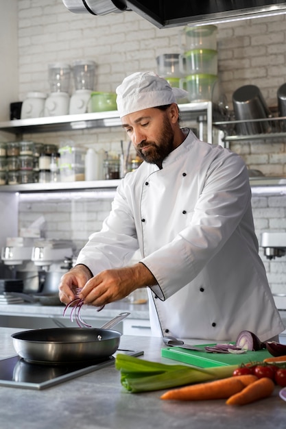 Free Photo male chef in the kitchen cooking dish in a frying pan