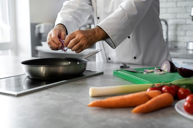 Free photo male chef in the kitchen cooking dish in a frying pan