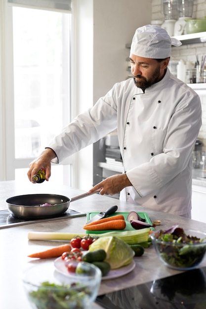 Male chef in the kitchen cooking dish in a frying pan