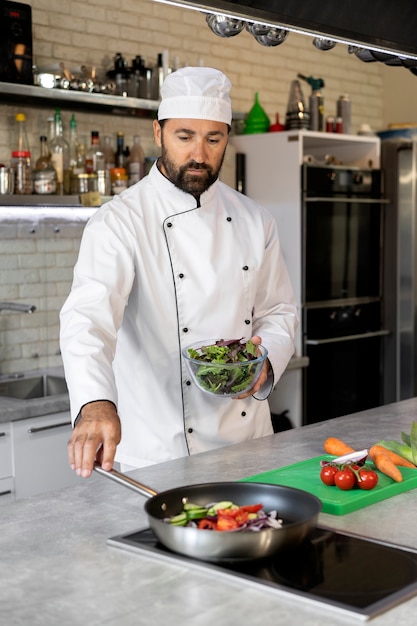 Free photo male chef in the kitchen cooking dish in a frying pan