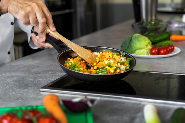 Free Photo male chef in the kitchen cooking dish in a frying pan