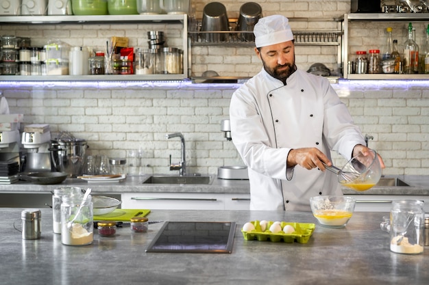 Free photo male chef in the kitchen using eggs to cook